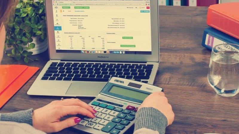 A legal bookkeeper reviewing a firm ledger and billing report at a desk