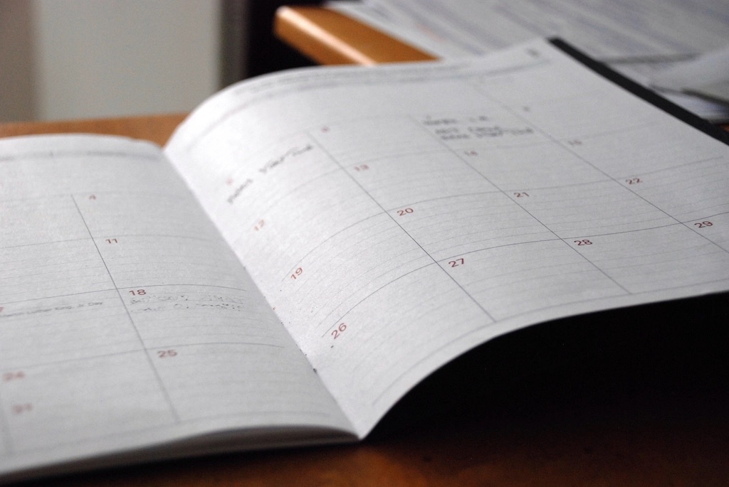 A lawyer reviewing a printed weekly calendar at their desk on a Monday morning with a pen and a coffee.