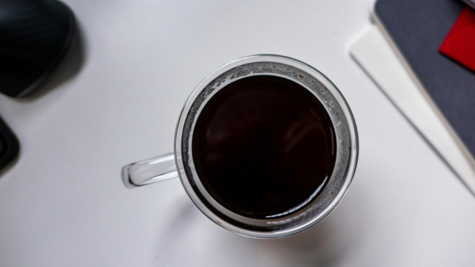 A lawyer at a desk with a coffee cup and open planner, drafting a weekly client update note.