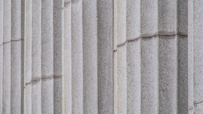 The stone facade and columns of a Canadian courthouse on a clear day