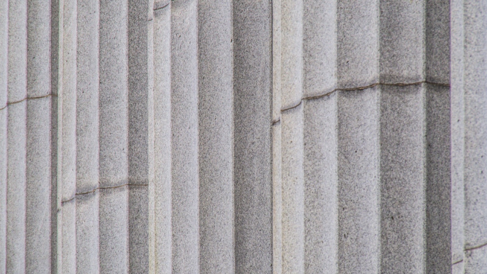 The stone facade and columns of a Canadian courthouse on a clear day
