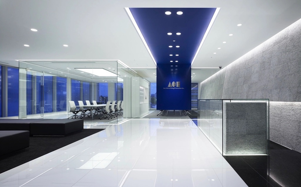 A warmly lit law firm reception desk with a receptionist smiling and gesturing toward a chair for a waiting visitor
