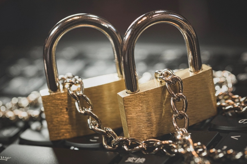 A brass padlock resting on a closed laptop beside a stack of client file folders on a lawyer's desk