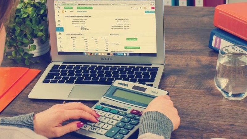 A card and calculator beside an invoice, representing an online payment being taken